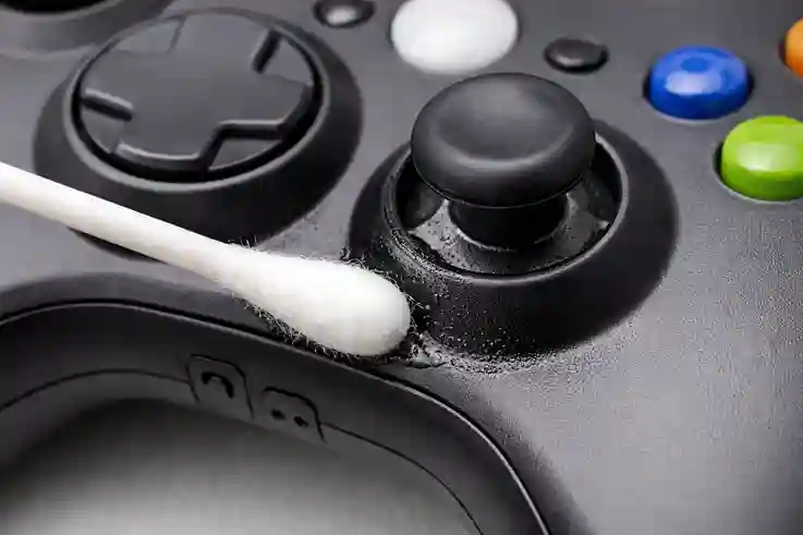 Close-up of cotton swab applying alcohol to the base of an analog stick